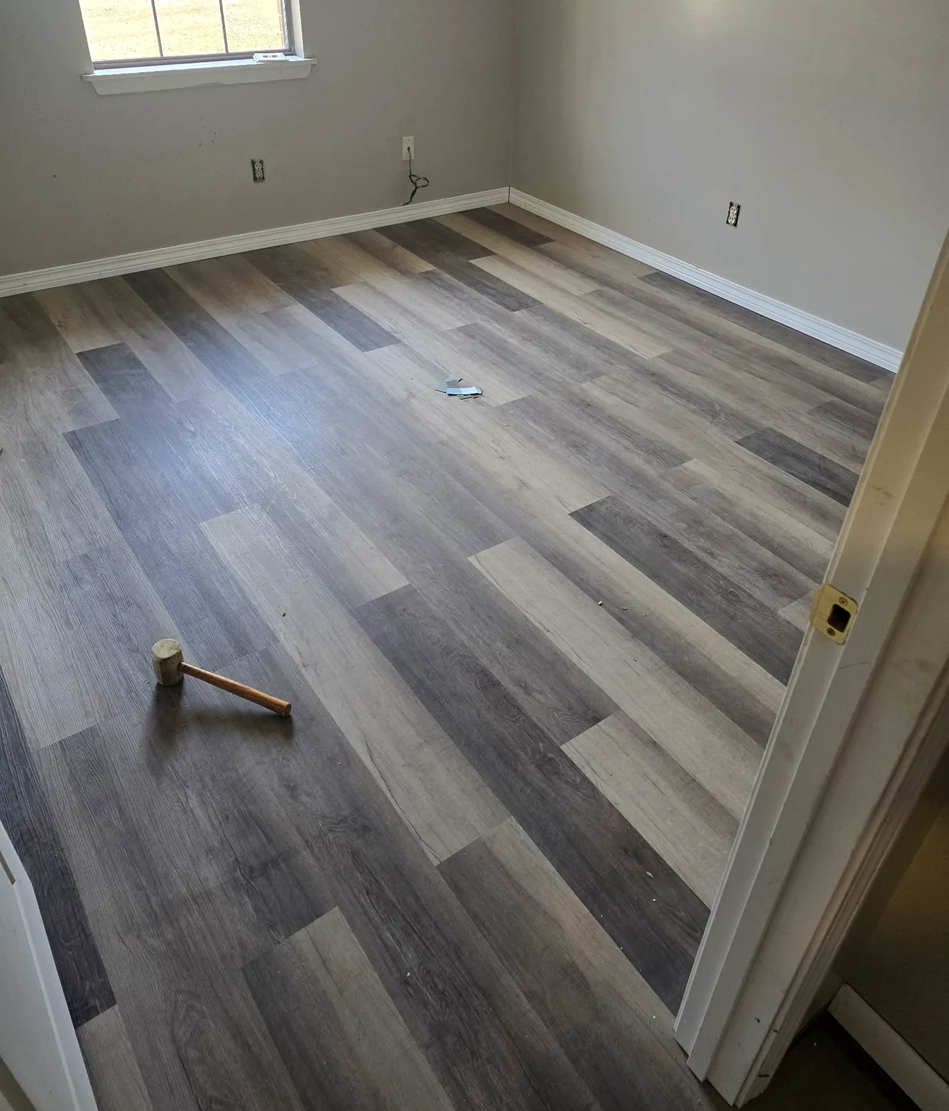 Bedroom with newly installed gray plank flooring and white baseboards